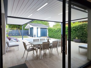 An outdoor patio with a table and chairs, a swing set, and a shed.