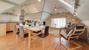 Une cuisine spacieuse avec un coin repas, un plancher en bois et un mur en pierre.