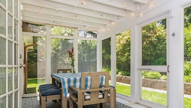 A conservatory with a table and chairs, large windows, and a patterned rug. - Classic Hamptons home in Springs.  Pool, lovely back yard and steps to the beach (East Hampton)