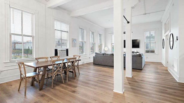 A spacious living area with a dining table and chairs, a sofa, and a television. - Charming Historic Loft in Downtown Galveston (Galveston)