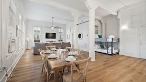 A spacious living area with a wooden dining table set for four, a sofa, and a bunk bed in the background. - Charming Historic Loft in Downtown Galveston (Galveston)