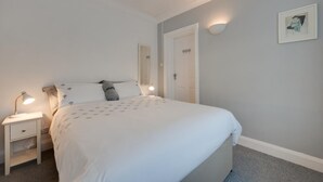 Ein Schlafzimmer mit einem Bett, Nachttischen, einer Wandlampe und einer Tür.