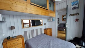 A bedroom with a bed, wooden dresser, bedside lamps, a window, and a door leading to another room. - 50m from ski slopes, 3rd floor, tv, ski locker, 35m², Les Arcs (Les Arcs)