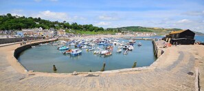 A harbor with numerous boats docked, a stone quay, and buildings in the background.