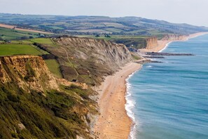 A coastal landscape with cliffs, a beach, and a distant village.