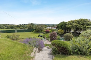 A well-maintained garden with a variety of plants and a clear pathway leading to a house.
