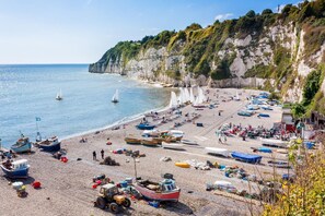 Ein Strand mit Booten, einem Traktor und Menschen.