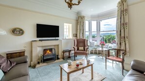 Ein Wohnzimmer mit Kamin, Fernseher und Blick ins Freie.