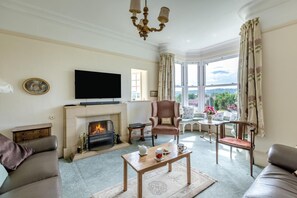Ein Wohnzimmer mit Kamin, Fernseher und Blick ins Freie.