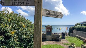 Een houten bord met richtingaanwijzingen naar Seaton en Branscombe, dat kustpaden markeert.