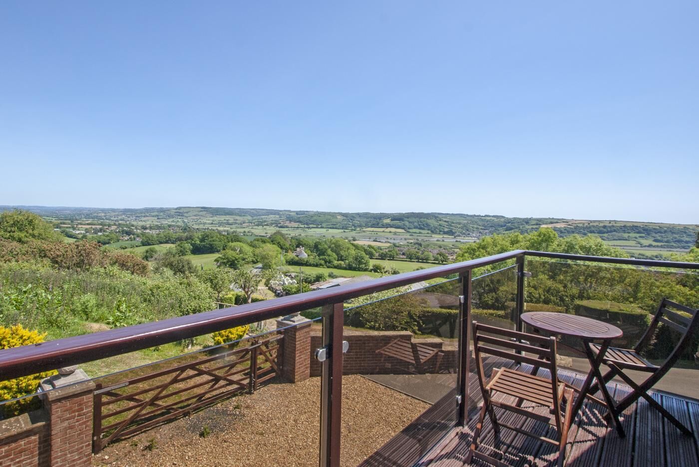 A balcony with a view of rolling hills and a distant village.