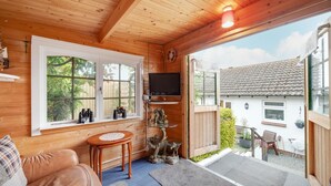 Une pièce chaleureuse, avec des murs en bois, une grande fenêtre, un téléviseur et une petite table.
