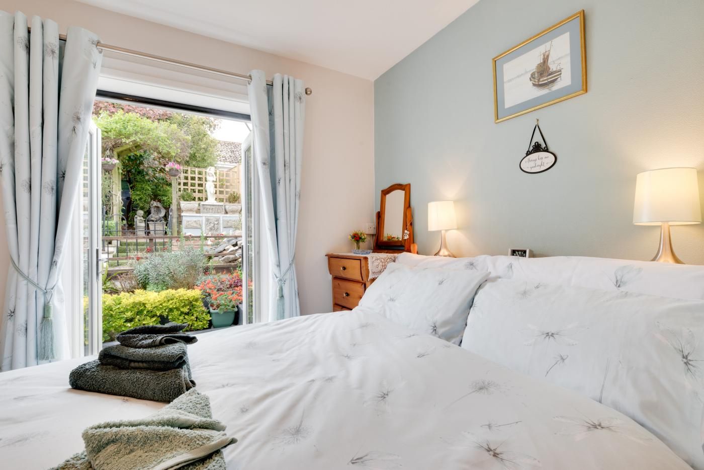 Un dormitorio con cama, cómoda, espejo y ventana con cortinas.