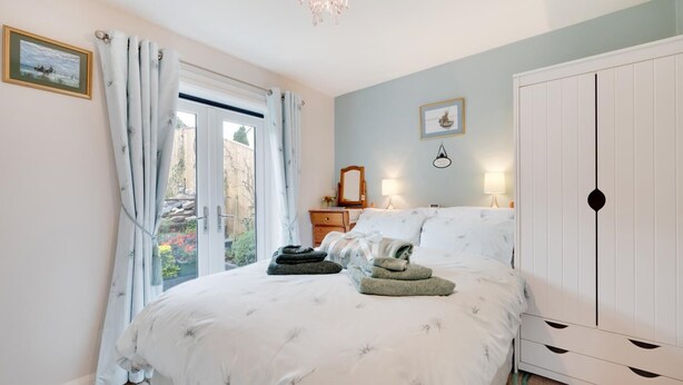Une chambre à coucher comprenant un lit, une commode, un miroir, une fenêtre avec des rideaux et une armoire.