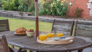A round wooden table with a tray, croissants, a bowl of strawberries, and glasses of orange juice. - 3 Bed in Seaton (oc-mbdal) (Seaton)