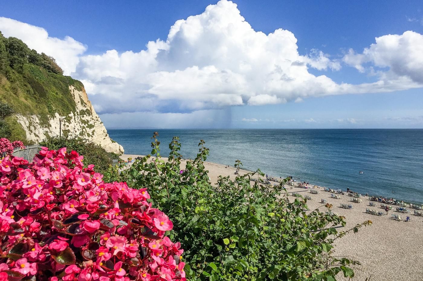 A coastal beach with a cliff, clear sky, and a view of the sea.