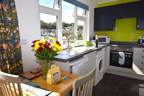 A modern kitchen with a view of the town, a washing machine, a microwave, and a dining area with a table and chairs.
