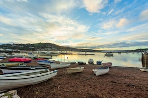 A harbor with boats docked on the shore and a bridge in the background.