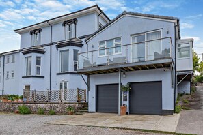Ein zweistöckiges Wohnhaus mit Garage, Balkon und einer Steinmauer mit Blumentöpfen.