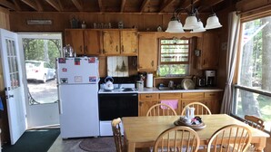 Una cocina de cabaña con armarios de madera, una estufa y una mesa de comedor con sillas.