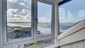 A room with a large window overlooking a coastal landscape.