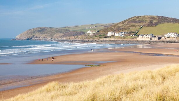 A coastal beach with grassy dunes, a sandy shore, and houses in the background. - 2 Bed in Braunton (oc-stabb) (Braunton)