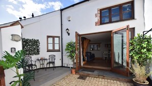 A white building with a patio area, a dining table with chairs, and a small garden. - 2 Bed in Braunton (oc-stabb) (Braunton)