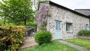 Una casa de piedra con un pequeño jardín, una puerta y una ventana.