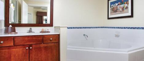 Un baño con tocador de madera, un espejo grande, una bañera blanca y un cuadro enmarcado en la pared.