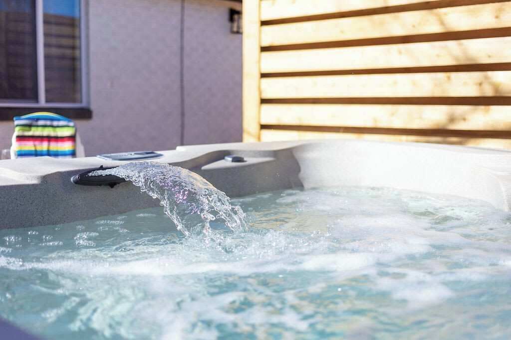 Un jacuzzi con agua saliendo, una toalla colorida a rayas y una pared de madera al fondo.