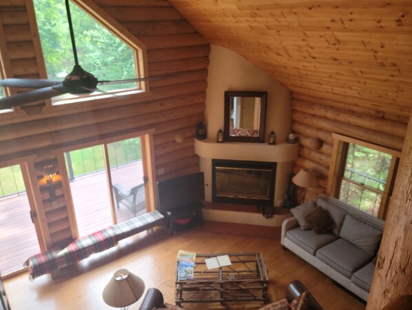 A cozy cabin interior with a fireplace, a sofa, a coffee table, and a bench.