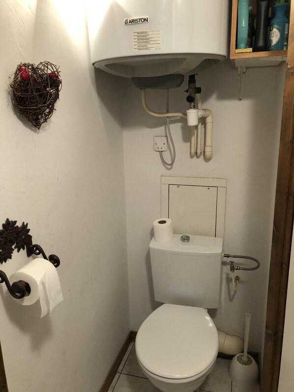 A small bathroom with a toilet, a bidet, and a water heater.