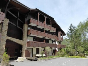 A multi-story building with balconies, stone facade, and a parking area. - 3rd floor, balcony, tv, ski locker, 51m², Les Contamines-Montjoie (Les Contamines-Montjoie)