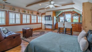 A spacious room with a large bed, a wooden ceiling, a television, a kitchen area with a bar, and a dining table with chairs. - St. George Oasis on 100 S – your cozy 1-bedroom retreat near Zion (St. George)