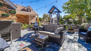 Ein Terrassenbereich im Freien mit einer Rattan-Couch, einem kleinen Tisch und Lichterketten.