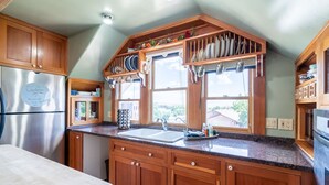 Eine Küche mit Holzschränken, einem Edelstahlkühlschrank, einer Spüle und einem Fenster mit Blick nach draußen.