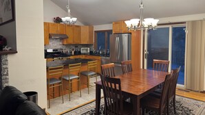 Une cuisine moderne avec des meubles en bois, un réfrigérateur en acier inoxydable et un coin repas comprenant une table et des chaises en bois.