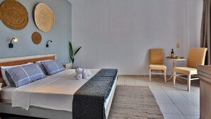 Une chambre d’hôtel moderne, équipée d’un lit, de deux fauteuils, d’une petite table et de quelques éléments décoratifs fixés au mur.