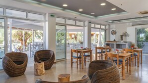 Un espace intérieur vaste et lumineux, doté de grandes fenêtres, de meubles en osier et d’un coin repas.