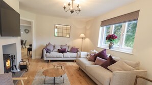 A cozy living room with a fireplace, two sofas, a coffee table, and a window with a view.