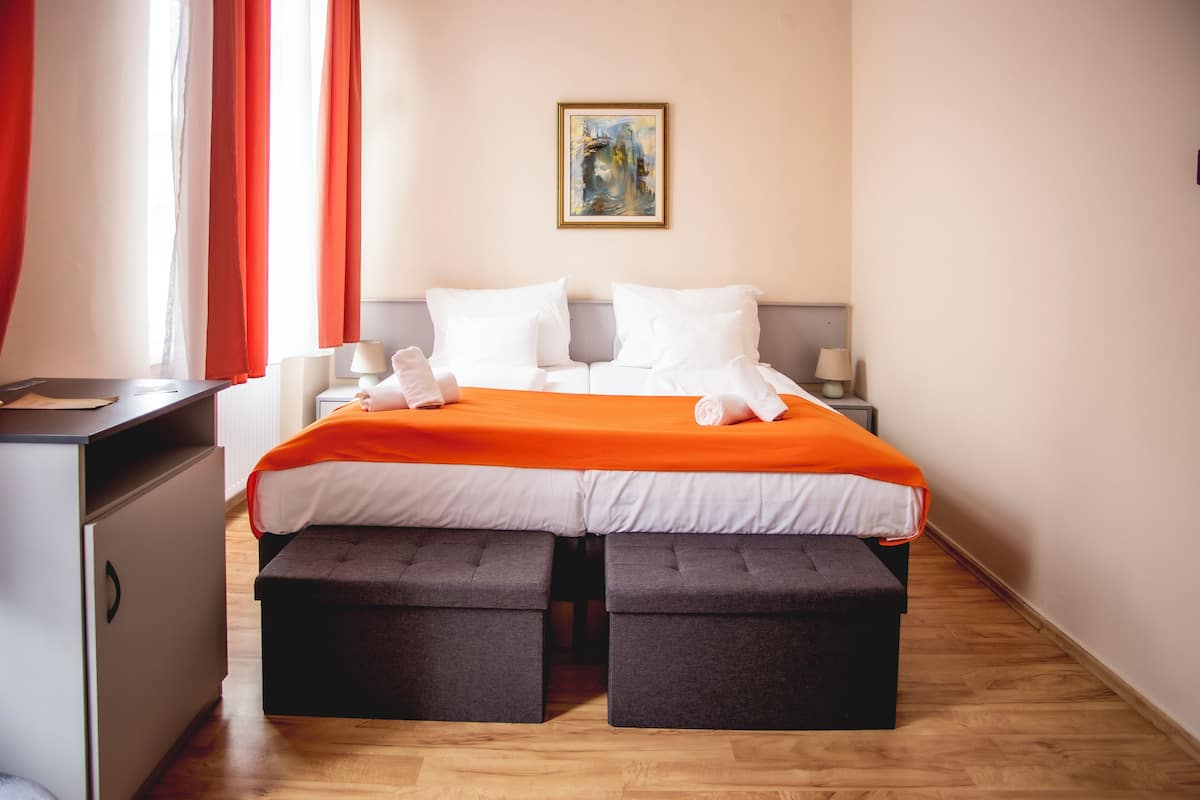 Ein Hotelzimmer mit einem Bett, zwei Nachttischen, einem Schreibtisch und einem Stuhl.