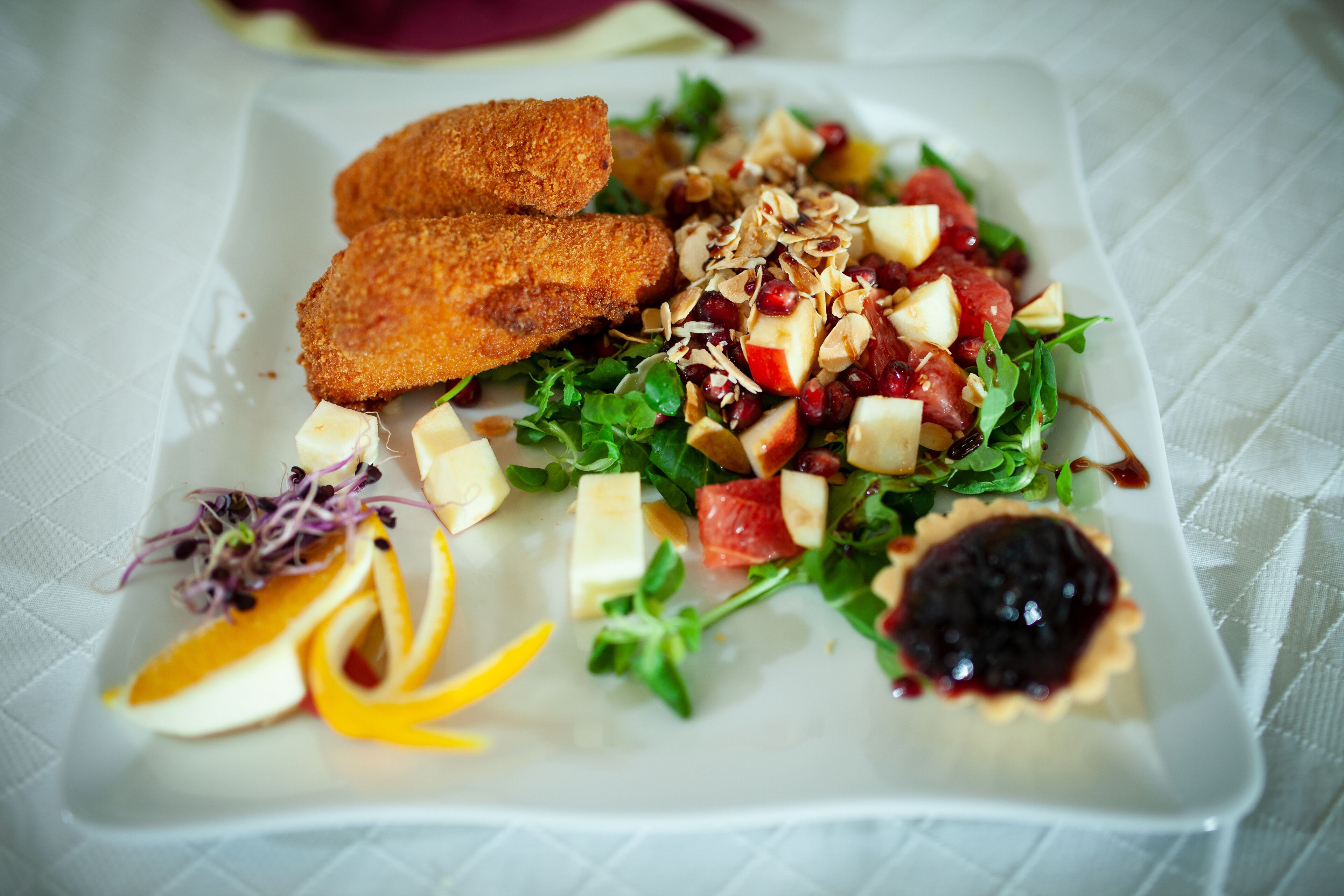 Une assiette comprenant une salade, deux plats panés et une petite tarte.