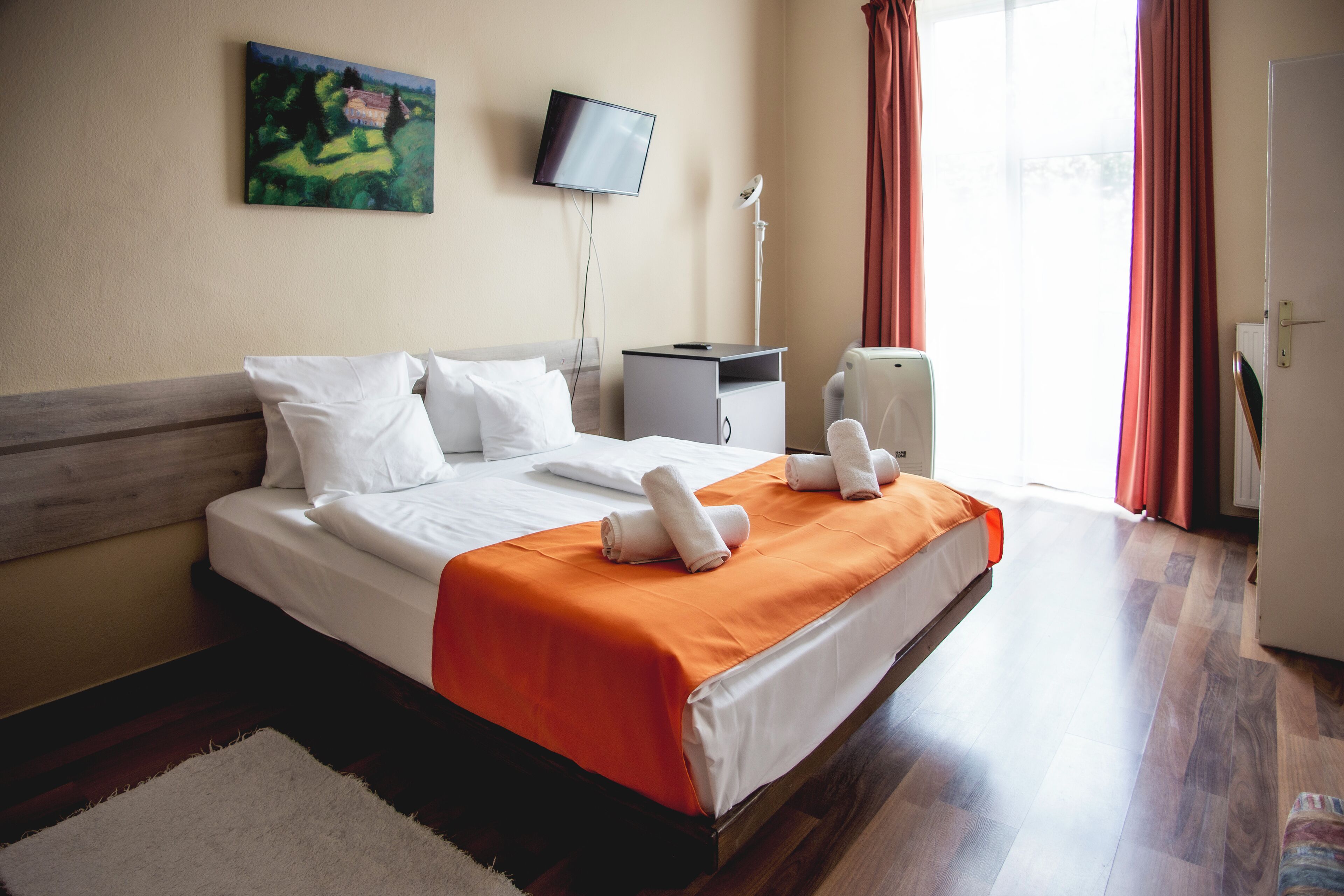 Habitación de hotel con cama, televisión de pantalla plana, escritorio y ventana con cortinas.