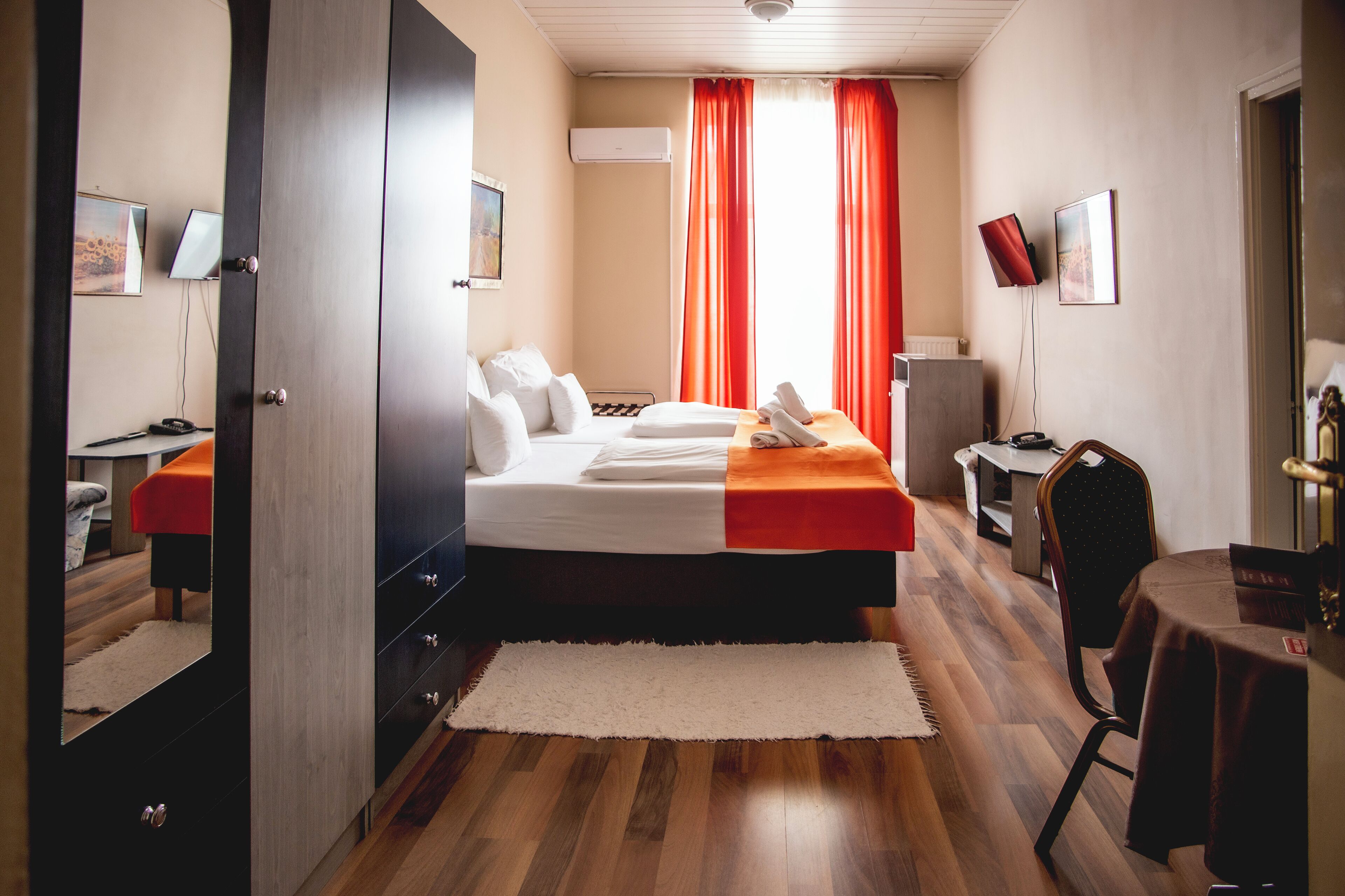 Quarto de hotel com cama, escrivaninha, cadeira e mesa.