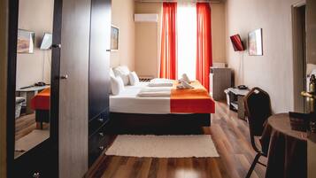 Quarto de hotel com cama, escrivaninha, cadeira e mesa.