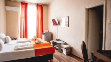 Une chambre d’hôtel avec deux lits, un bureau, une chaise, une petite table et un téléviseur.