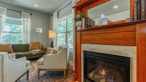 A cozy living room with a fireplace, a sofa, a chair, and a rug.