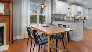 A modern kitchen with white cabinets, a wooden dining table, and black chairs.