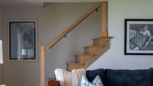A living room with a dark blue sofa, a wooden staircase, and a patterned rug. - Waterfront Tilghman Retreat with Dock, Fire Pit & Sunsets (Tilghman Island)