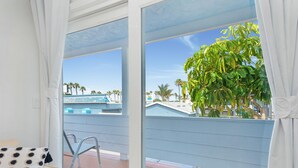 A balcony with a view of a building and palm trees.